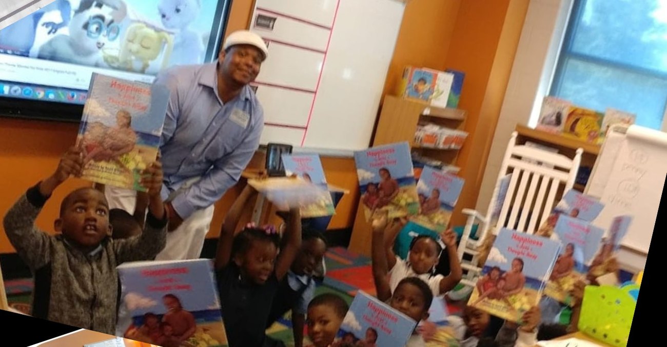 A classroom of children holding up copies of Happiness is Just a Thought Away, with David D. Gibson Sr. standing among them